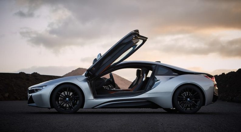 A silver BMW i8 is shown from the side with the doors open after leaving a used car dealership.