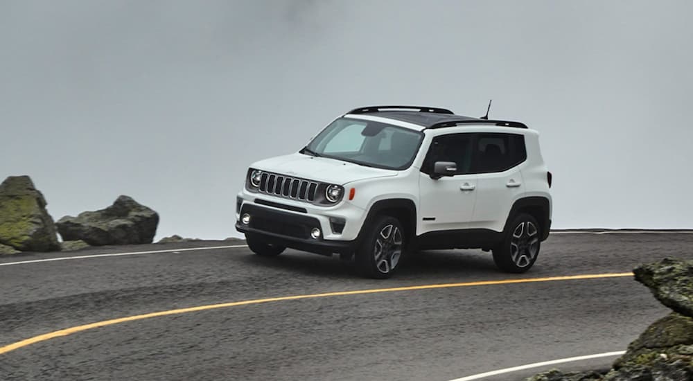 A white 2020 Jeep Renegade is shown from the front at an angle while rounding a bend.