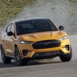 A yellow 2022 Ford Mustang Mach E is shown from the front at an angle while sliding during a 2022 Ford Mustang Mach-E vs 2022 Tesla Model Y comparison.