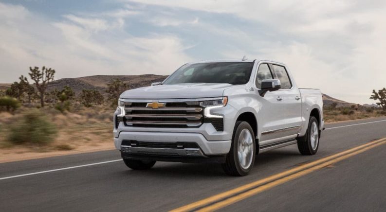 A white 2022 Chevy Silverado 1500 High Country is shown from the front at an angle during a 2022 Chevy Silverado 1500 vs 2022 Nissan Titan comparison.