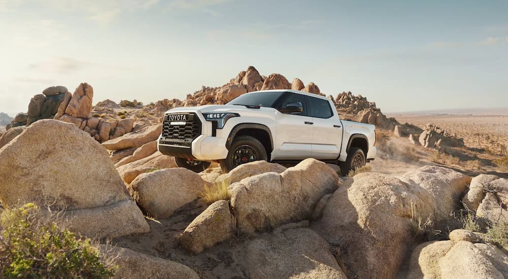 A white 2022 Toyota Tundra TRD Pro is shown off-roading on rocky terrain.