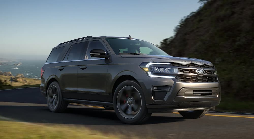 A grey 2022 Ford Expedition is shown driving on a coastal road.