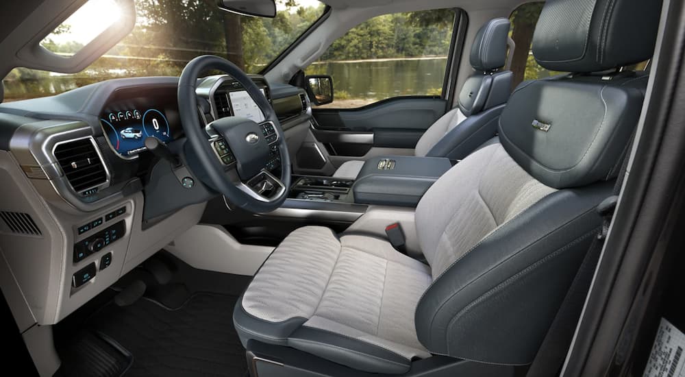 The grey and white interior of a 2022 Ford F-150 shows the steering wheel.