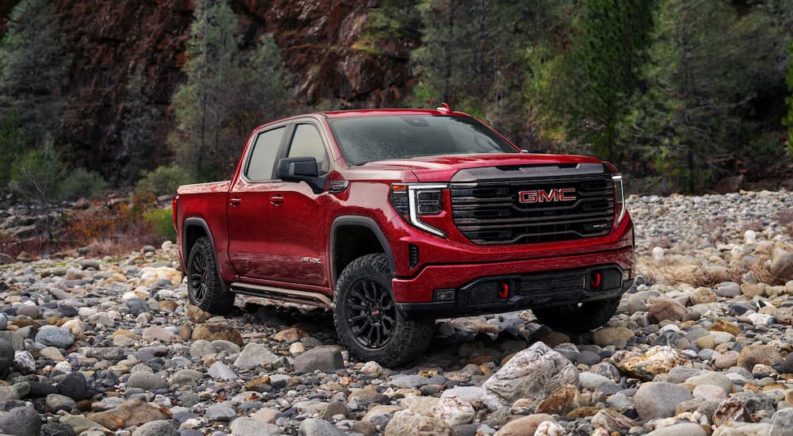 A red 2022 GMC Sierra 1500 AT4X is shown parked on a rocky trail during a 2022 GMC Sierra 1500 AT4 vs 2022 GMC Sierra 1500 AT4X comparison.