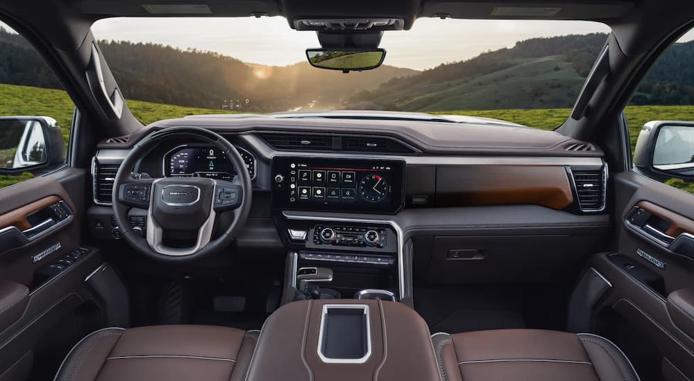 The black and brown interior of a 2022 GMC Sierra 1500 Denali shows the steering wheel and center console.