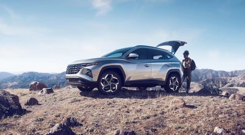 A silver 2022 Hyundai Tuscon is shown from the side on top of a mountain after the owner searched 'car dealer near me'.