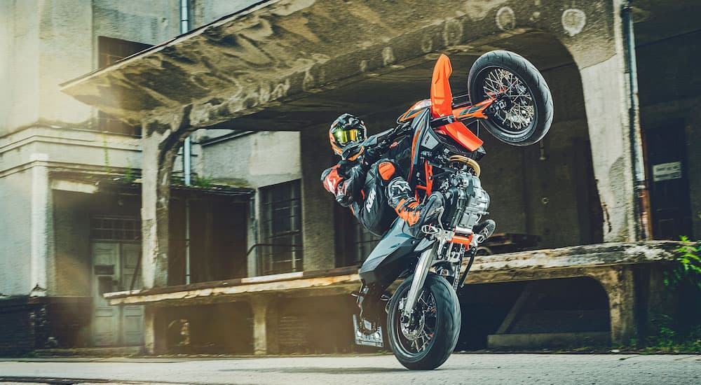 A 2022 KTM SMC 690 R is shown from the front while doing a wheelie in a warehouse.