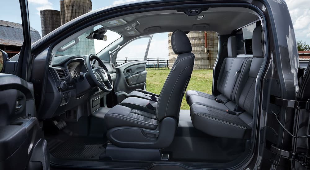 The black interior of a 2022 Nissan Titan King Cab is shown from the side with the doors open.