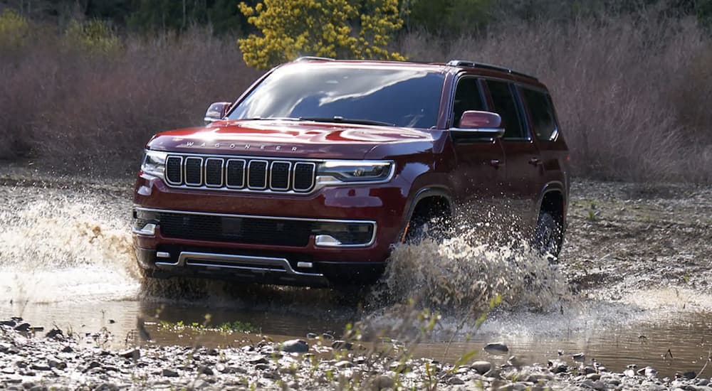 A red 2022 Wagoneer is shown from the front off-roading through a river.
