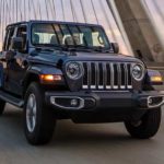 A grey 2022 Jeep Wrangler is shown from the front at an angle while driving over a bridge after leaving a used Jeep dealer.