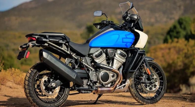 A blue 2022 Harley-Davidson Pan-American is shown from the side at an angle while parked off-road after leaving a 'Harley-Davidson Dealer near me'.