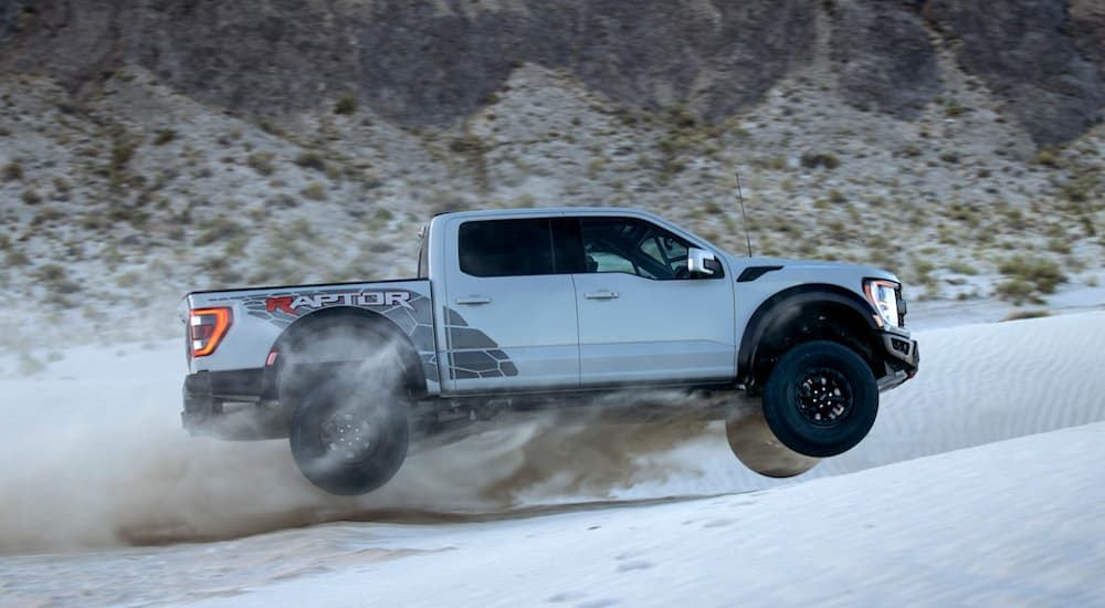 A silver 2023 Ford F-150 Raptor R is shown from the side while jumping in the desert.