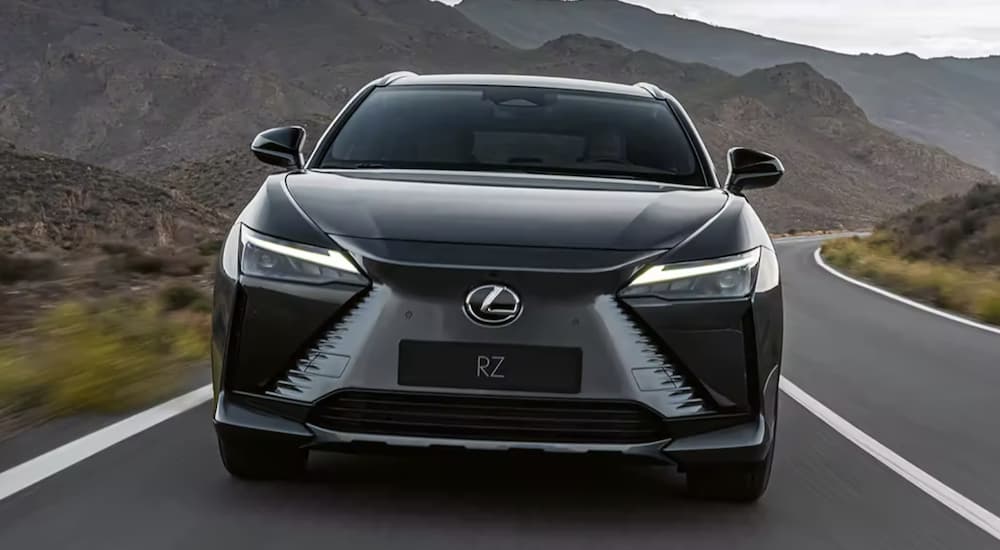 A grey 2023 Lexus RZ is shown from the front driving on an open road.
