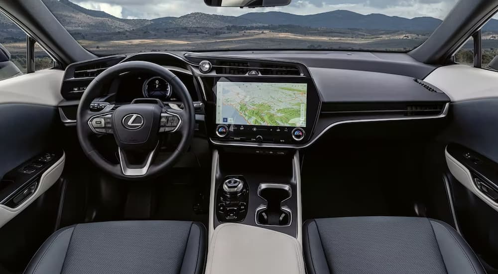 The black interior of a 2023 Lexus RZ shows the steering wheel and infotainment screen.