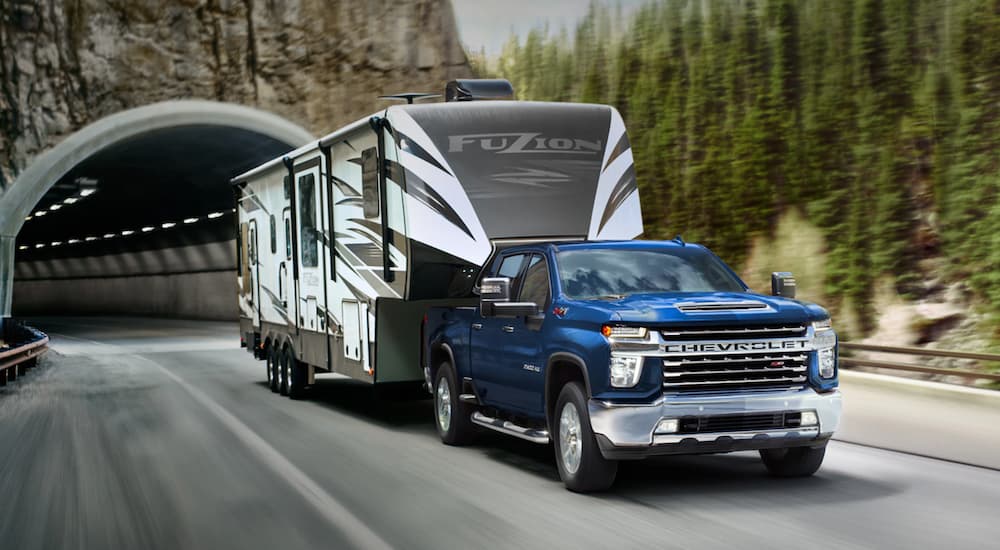 A blue 2022 Chevy Silverado 2500HD is shown from the front at an angle while towing a camper after leaving a Chevy dealer.