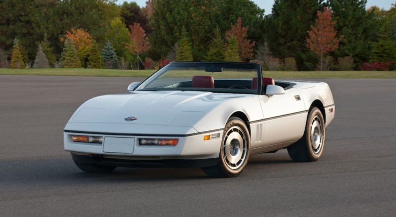 A white 1987 a Chevy Corvette is shown parked in an empty lot.