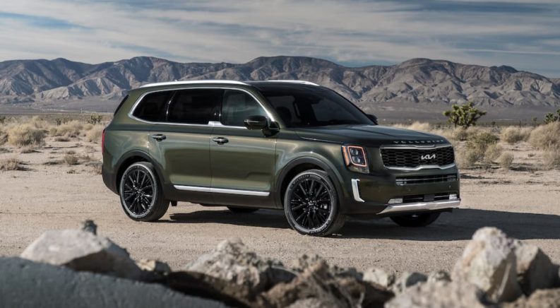 A green 2022 Kia Telluride is shown parked on a sandy lot.