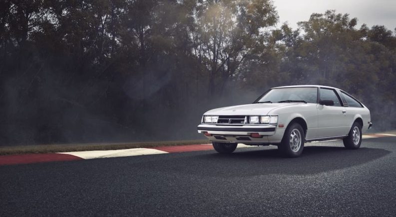 A white 1979 Toyota Celica Supra is shown on a race track after visiting a Naperville Toyota dealer.