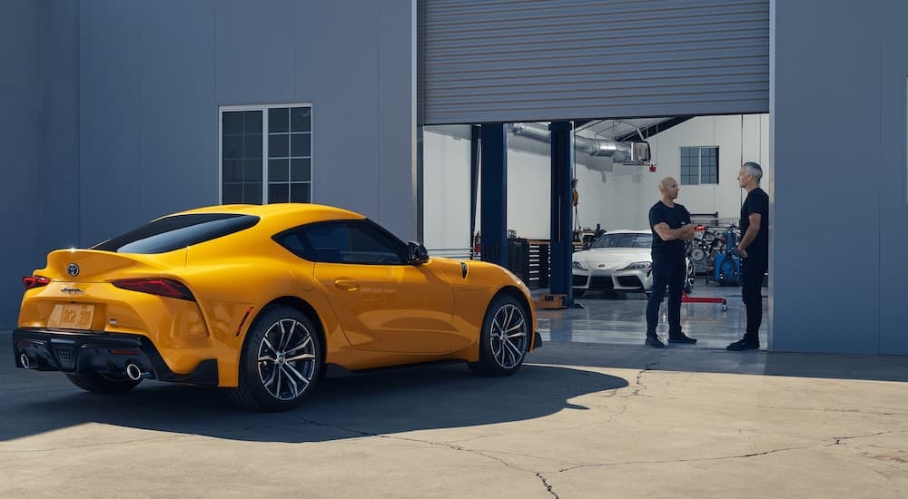 A yellow 2020 Toyota Supra GR is shown parked near a garage.