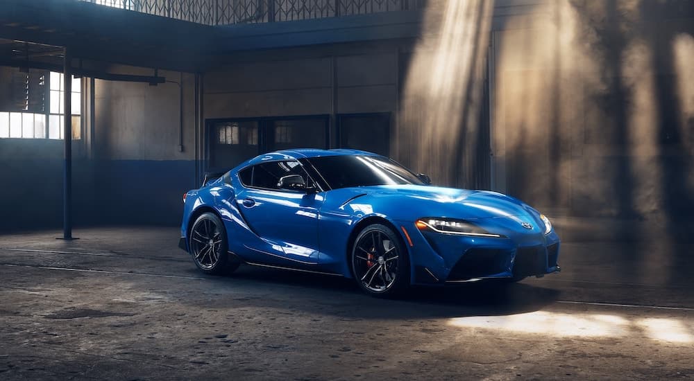 A blue 2021 Toyota Supra GR is shown parked inside a warehouse.