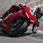 A red 2022 Ducati Panigale V2 is shown from the front while rounding a corner on a racetrack.