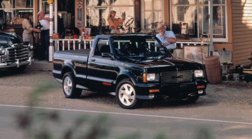 A black 1991 GMC Syclone is shown parked outside of a store.