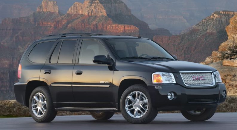 A black 2009 GMC Envoy Denali is shown parked with a canyon view after leaving a used GMC dealership.