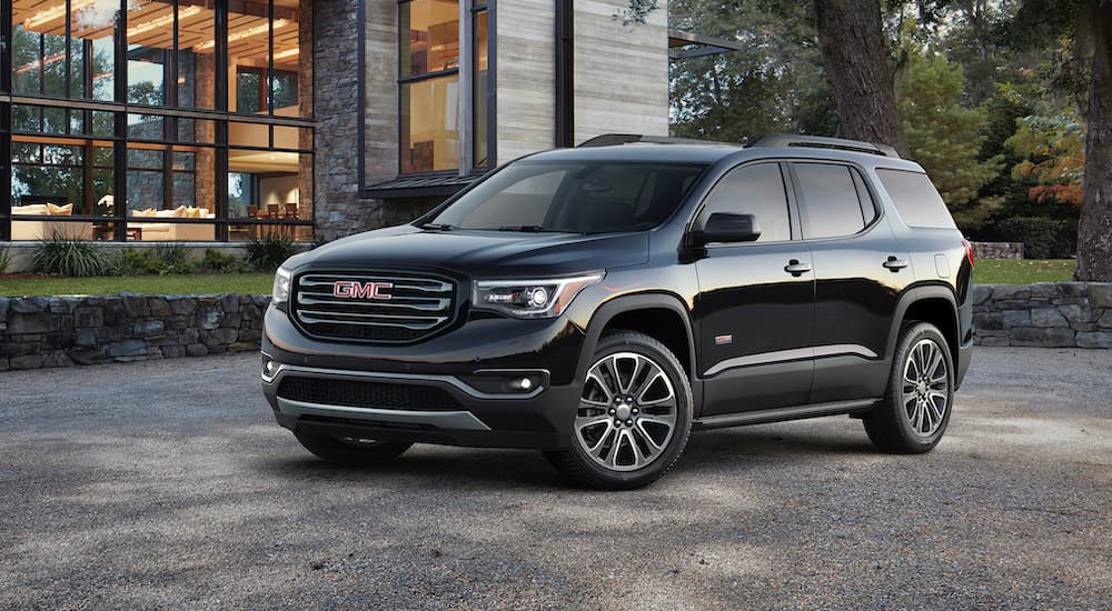 A black 2017 GMC Acadia is shown parked outside of a home.