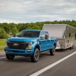 A blue 2022 Ford F-250 Tremor is shown from the front while towing a camper.