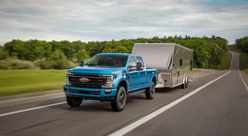 A blue 2022 Ford F-250 Tremor is shown from the front while towing a camper.