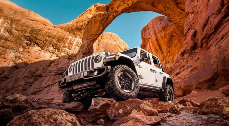 A white 2020 Jeep Wrangler Rubicon is shown from the front while driving off-road after leaving a dealership that advertise used Jeep Wrangler for sale.
