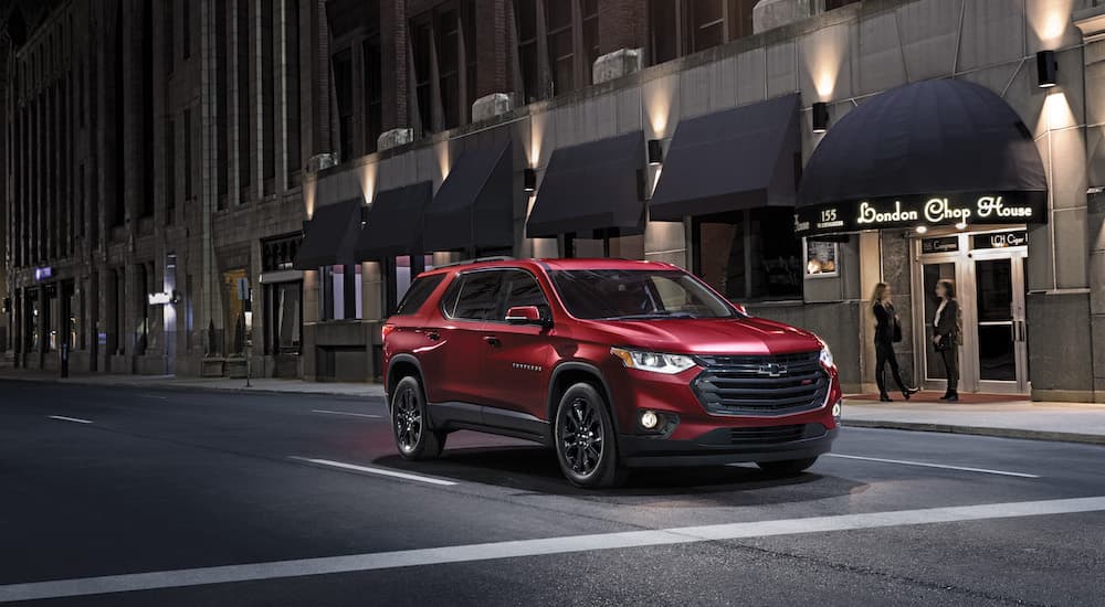 A red 2023 Chevy Traverse is shown from the front at an angle while driving on a city street.