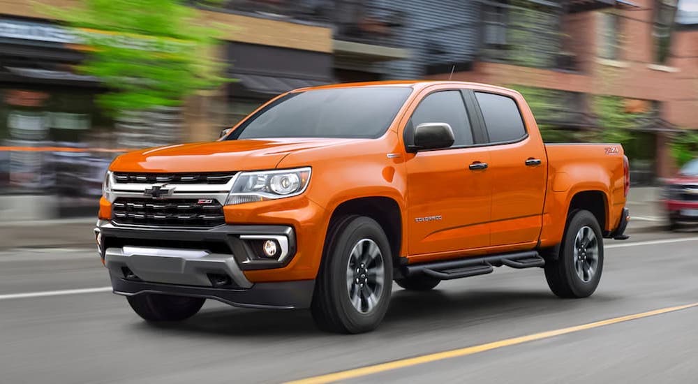 An orange 2022 Chevy Colorado Z71 is shown from the front at an angle in an urban area.