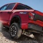 A red 2022 Nissan Titan Pro4X is shown from the rear at a low angle while driving off-road.