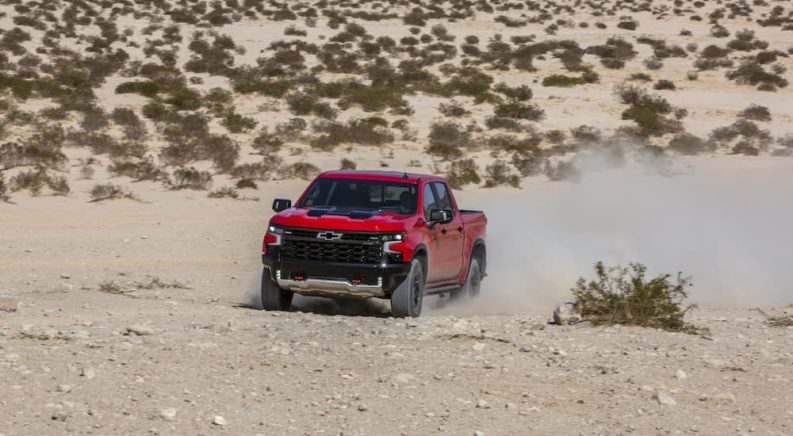 A red 2022 Chevy Silverado 1500 ZR2 is shown from the front while driving off-road after leaving a Chevy Silverado 1500 dealer.