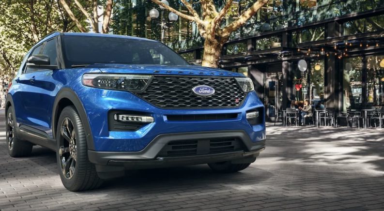 A blue 2022 Ford Explorer ST Atlas is shown parked outside of a restaurant.