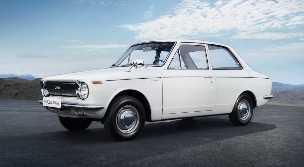 A white 1966 Toyota Corolla is shown parked in an open lot.