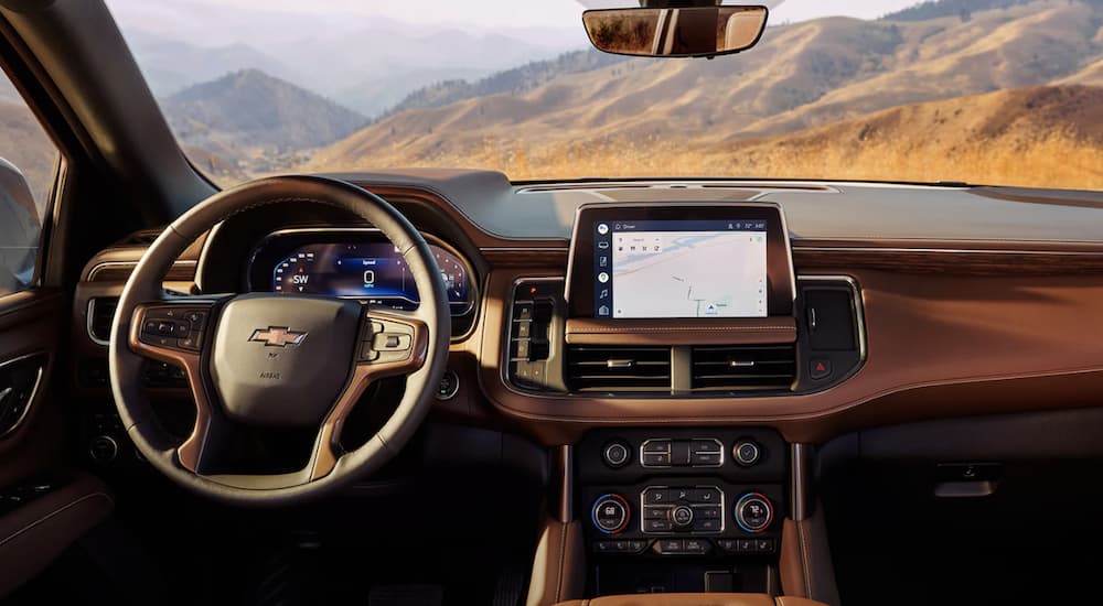 The tan interior of a 2023 Chevy Suburban shows the steering wheel and infotainment screen.