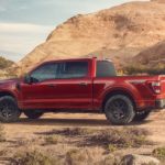 A red 2023 Ford F-150 Rattler is shown from the rear at an angle while parked in a desert.