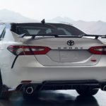 A white 2023 Toyota Camry TRD is shown from the rear while parked in a hangar.