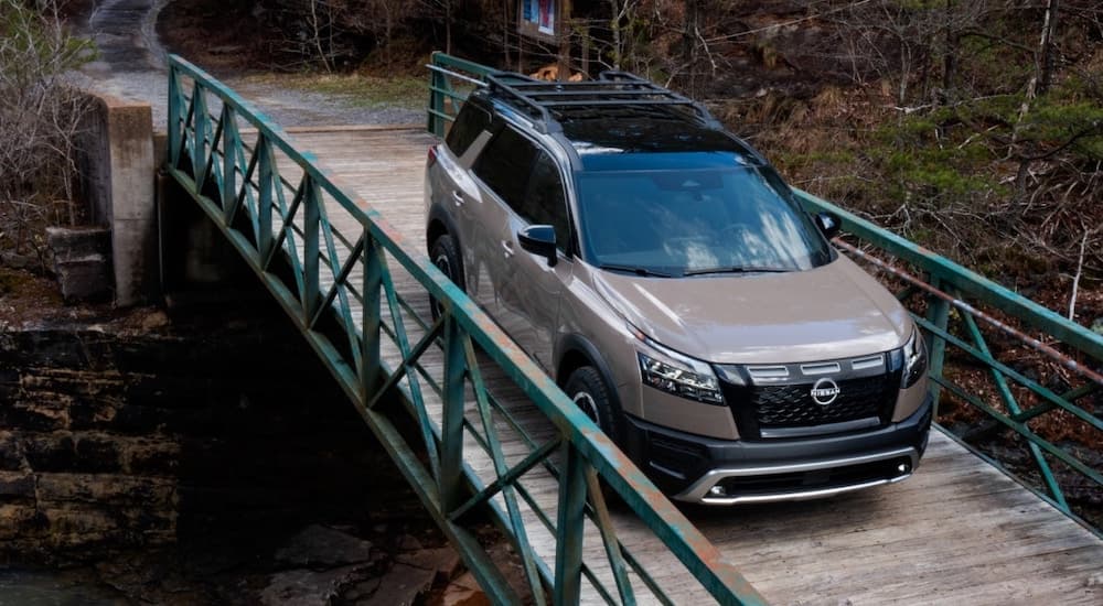 A brown 2023 Nissan Pathfinder is shown from the front while crossing a bridge after leaving a dealer that sells Nissan SUVs.