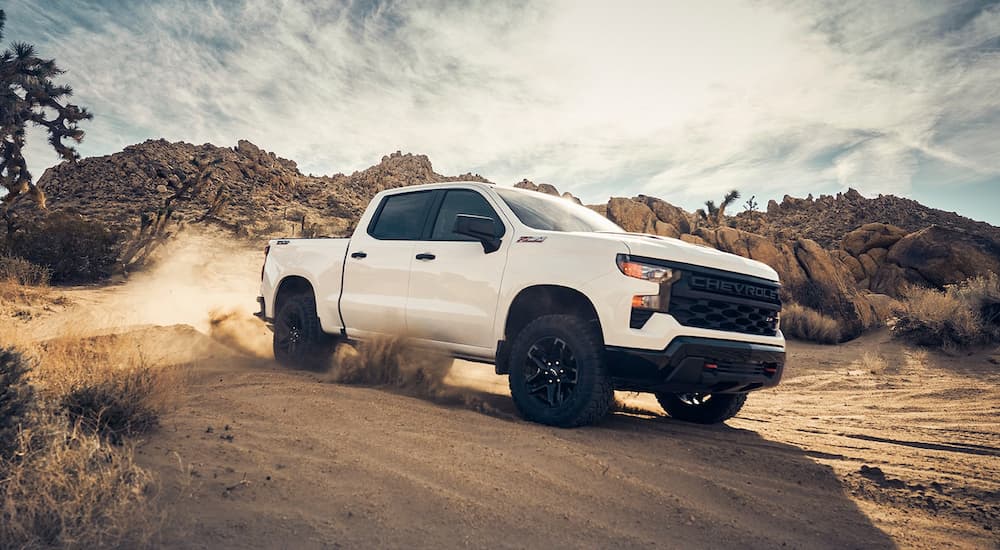 A white 2022 Chevy Silverado 1500 Z71 Trailboss is shown kicking up dirt in the dunes.