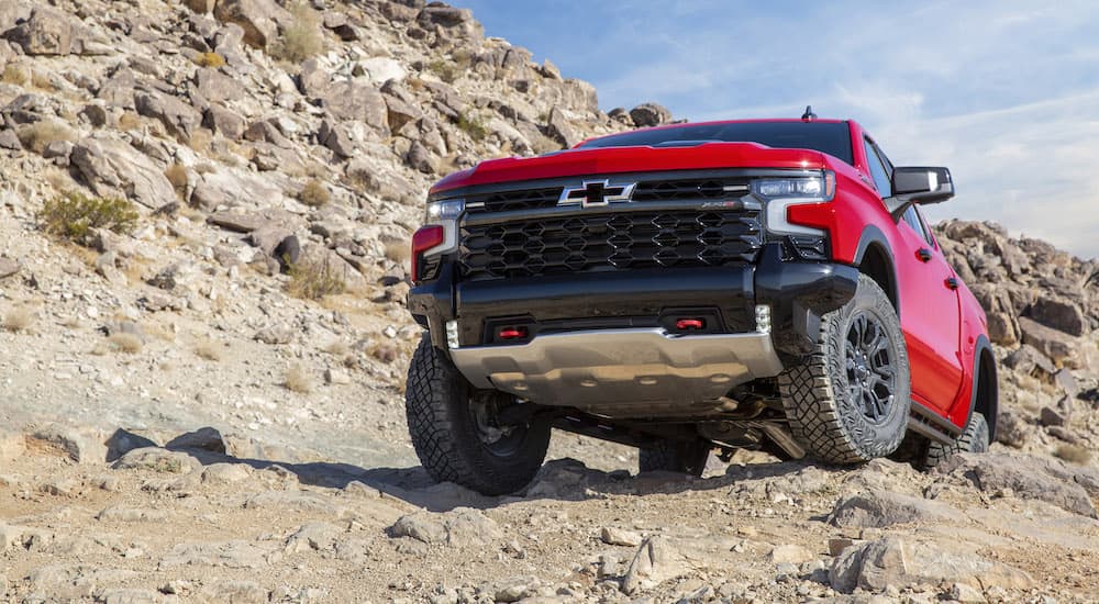 A red 2022 Chevy Silverado 1500 ZR2 is shown crawling over rocks.