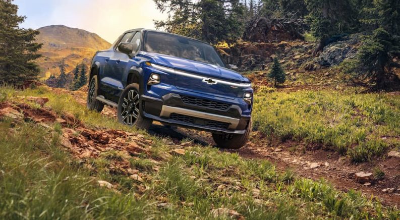 A blue 2024 Chevy Silverado EV RST is on a trail after visiting Chevy dealers in Cincinnati.