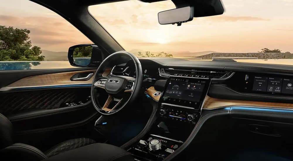 The black interior of a 2022 Jeep Grand Cherokee 4xe shows the steering wheel and infotainment screen.