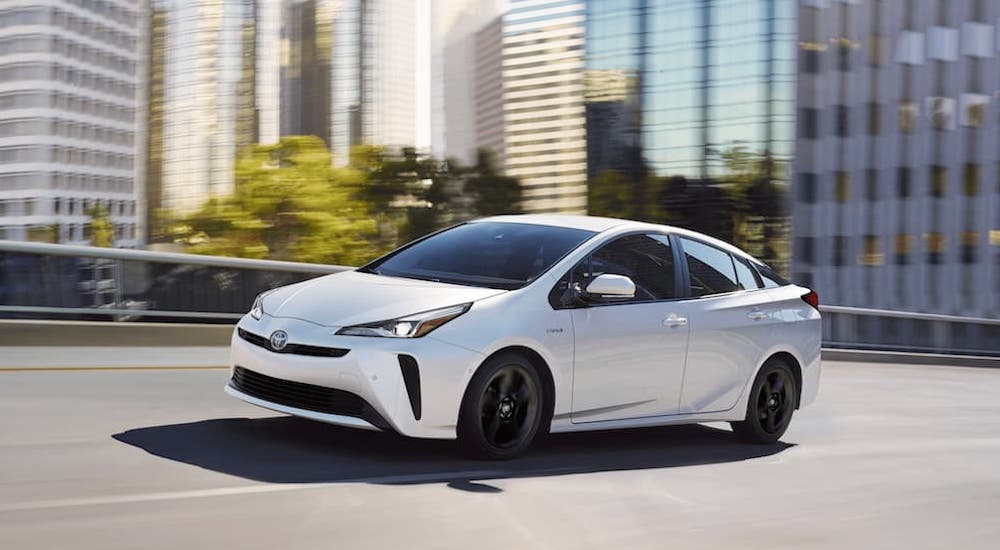 A white 2020 Toyota Prius is shown from the front at an angle on a city street.