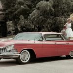 A red 1959 Buick LeSabre is shown parked outside of a home.