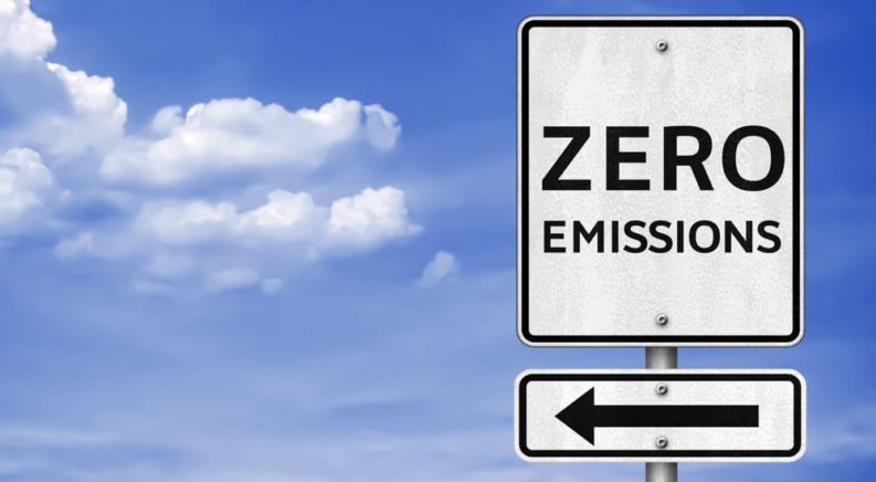 A sign that says 'zero emissions' is shown against a blue sky.