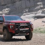 A red 2023 GMC Canyon AT4X is shown from the front at an angle while driving off-road.
