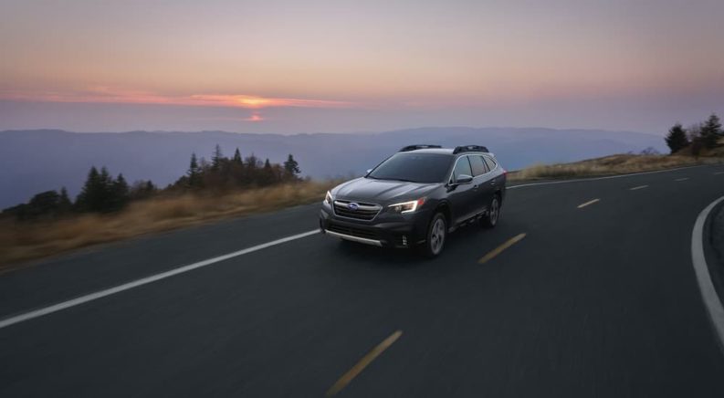 A dark grey 2020 Subaru Outback is shown on a mountain road.